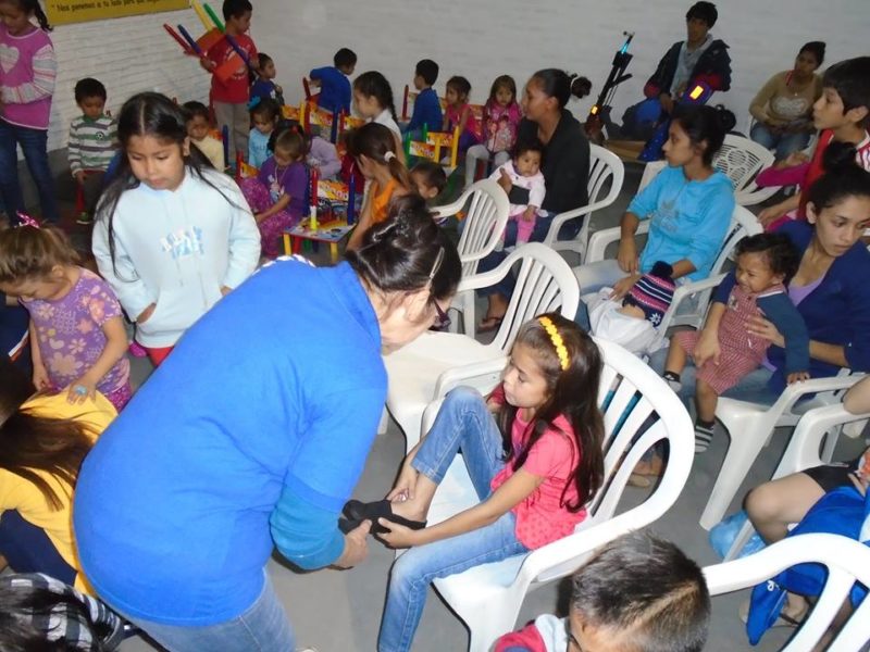 Las profes probando a cada niño o niña los zapatos de su calce.